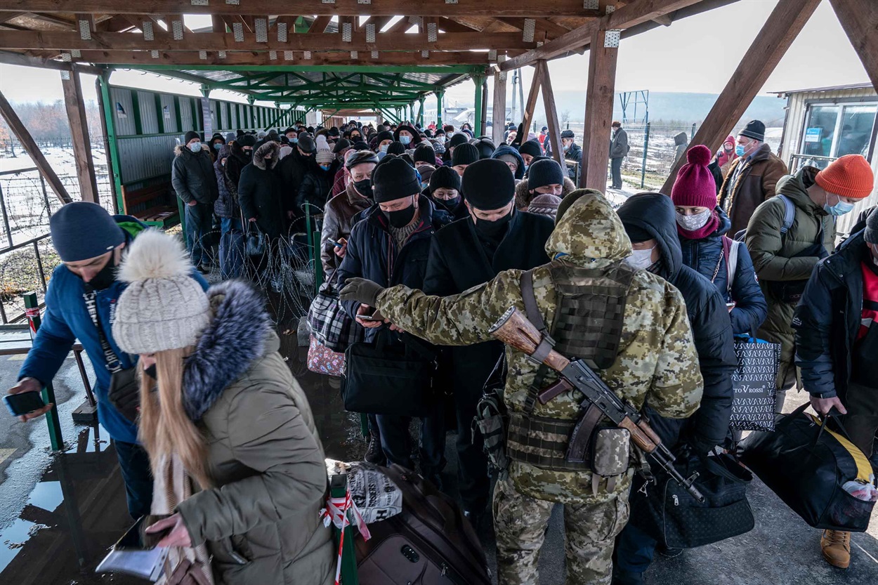 Військовослужбовець української прикордонної служби перевіряє мобільний додаток DIA, коли люди входять до пункту пропуску у Станиці Луганській