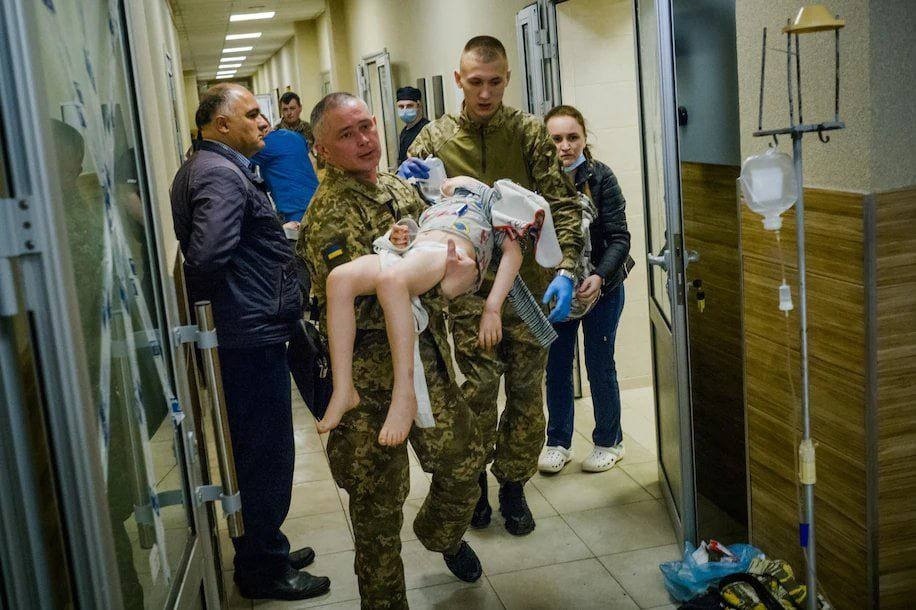 Поранену дитину несуть на руках у лікарню після обстрілу вокзалу. 