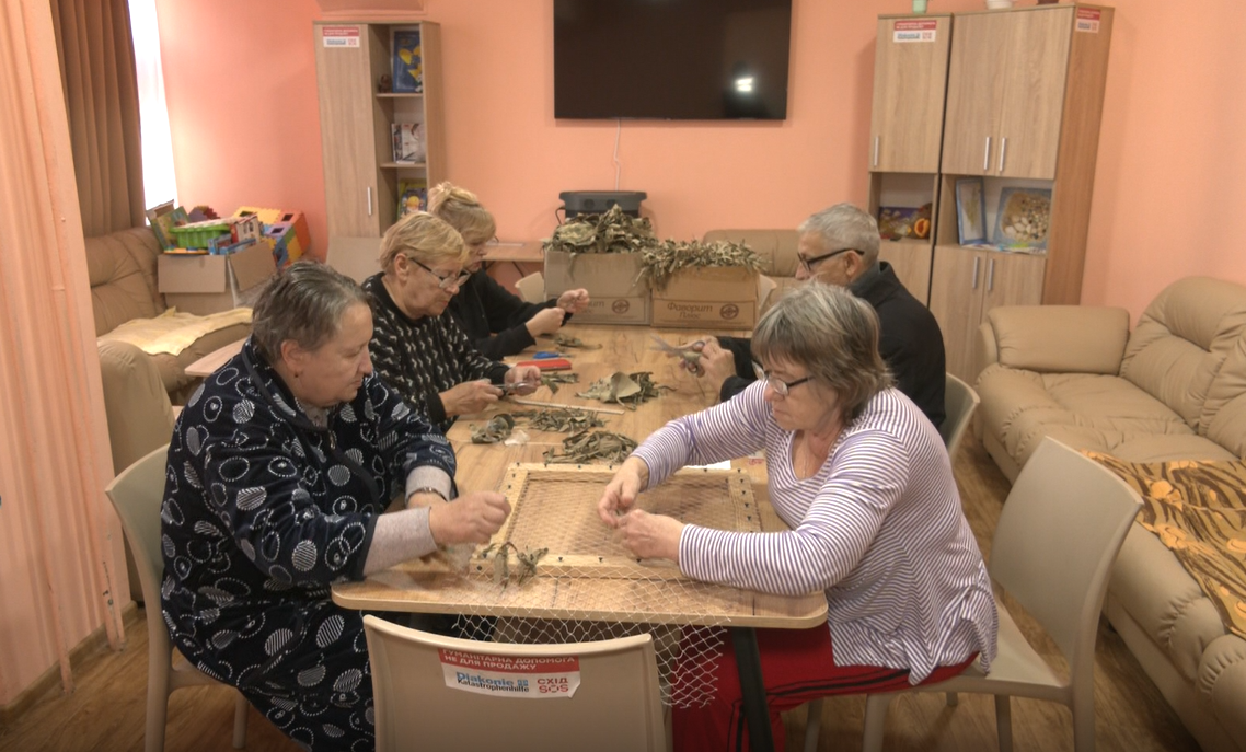 Мешканці шелтера плетуть маскувальні сітки для шлемів військових