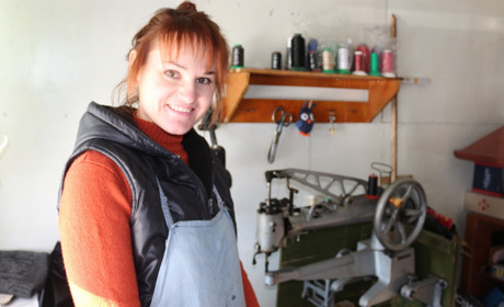 Люди заглядають у вікно майстерні і дивуються: жінка ремонтує взуття