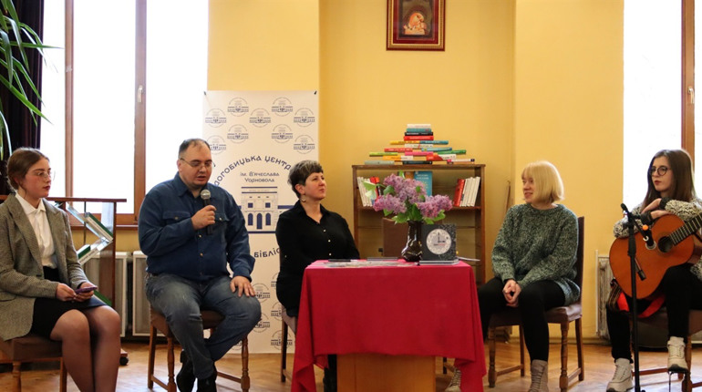Стос книг, авторські листівки та квіти у вазах — презентація поетичної збірки «Дроhema»
