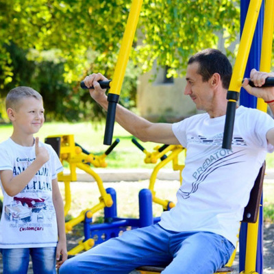 Олександр Гребенюк з сином Матвієм на тренажерах в парку